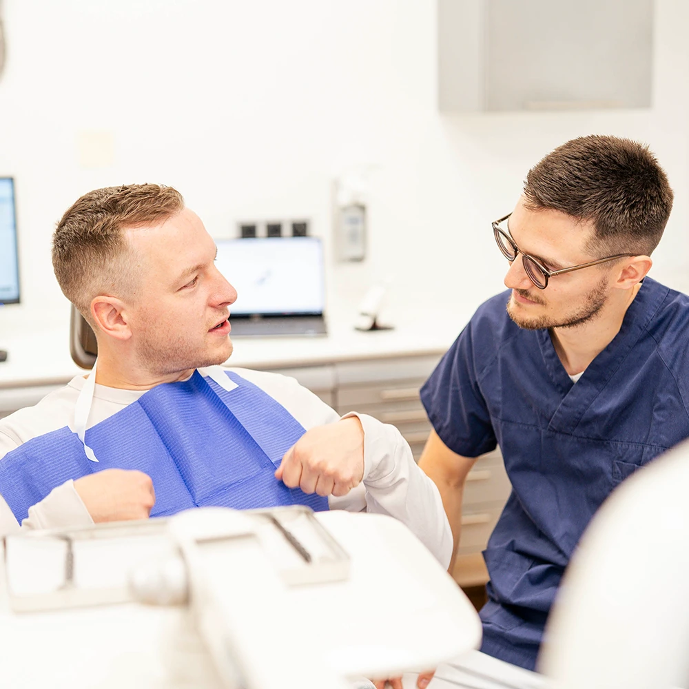 Zahnarzt berät einen Patienten in der Praxis bei einer Zahnbehandlung mit Füllung