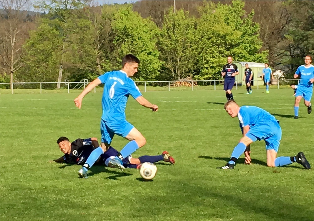 Fußballspieler kämpfen um den Ball auf dem Rasen bei einem Amateurspiel im Freien.