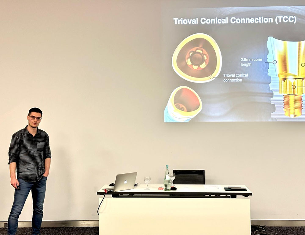 Zahnarzt Niklas Scherg steht in der Praxis vor einer Präsentation zur Trioval Conical Connection (TCC) Hightech-Zahnbehandlung
